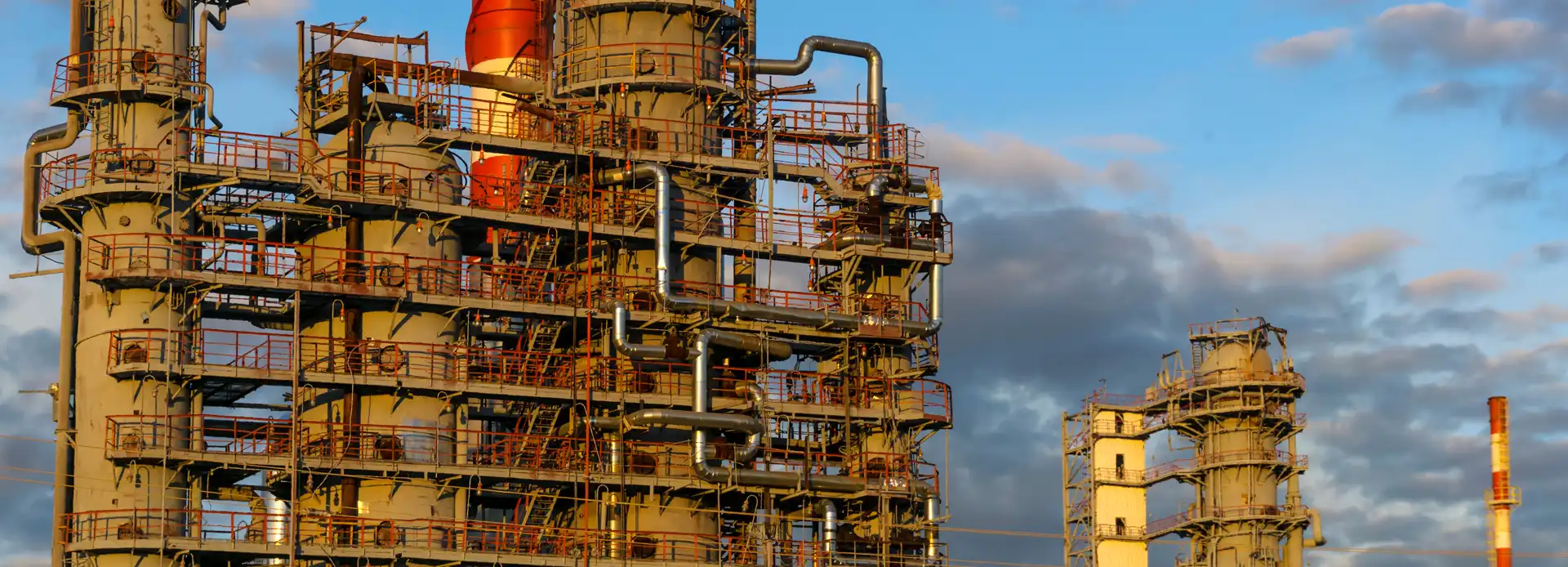 Industrial chemical processing towers with piping and platforms against the sky